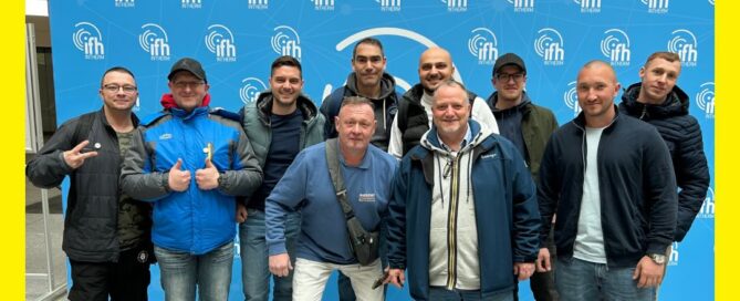 Team Günther posiert vor einer Werbewand auf der Messe.