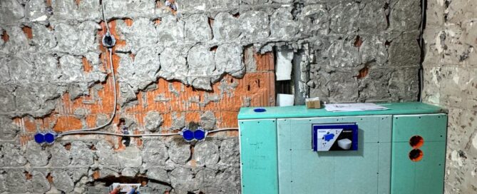 Wände eines Badezimmers, die vom Putz befreit wurden, um darunter leitungen zu verlegen und eine Vorwandinstallation eines neuen WCs.