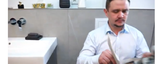 Ein Mann liest Zeitung auf dem Klo.