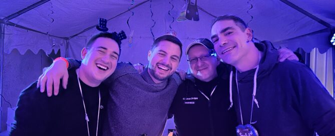 Mitarbeiter und der Chef lachen am Firmen-Oktoberfest gemeinsam in die Kamera.