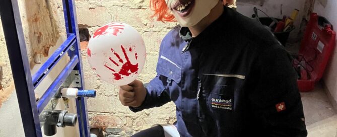 Ein als Horror-Clown verkleideter Mitarbeiter der Firma Günther am arbeiten an sanitärtechnischen Anlagen.