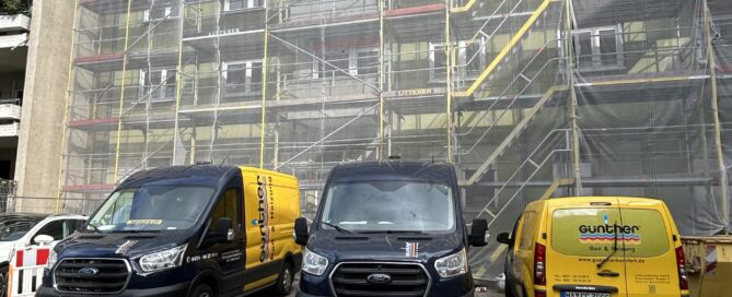 Drei Firmenwagen der Günther GmbH aus Mannheim stehen vor einem Baugerüst.