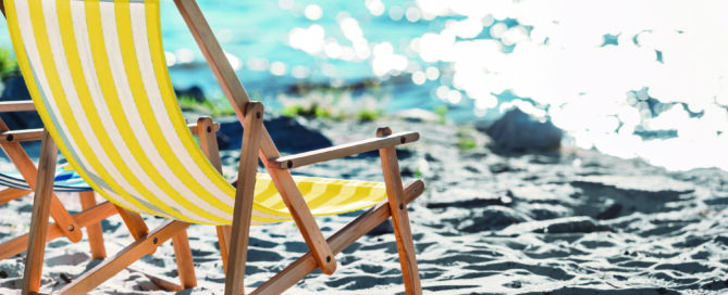 Ein Liegestuhl steht am Strand mit Blick aufs Meer.